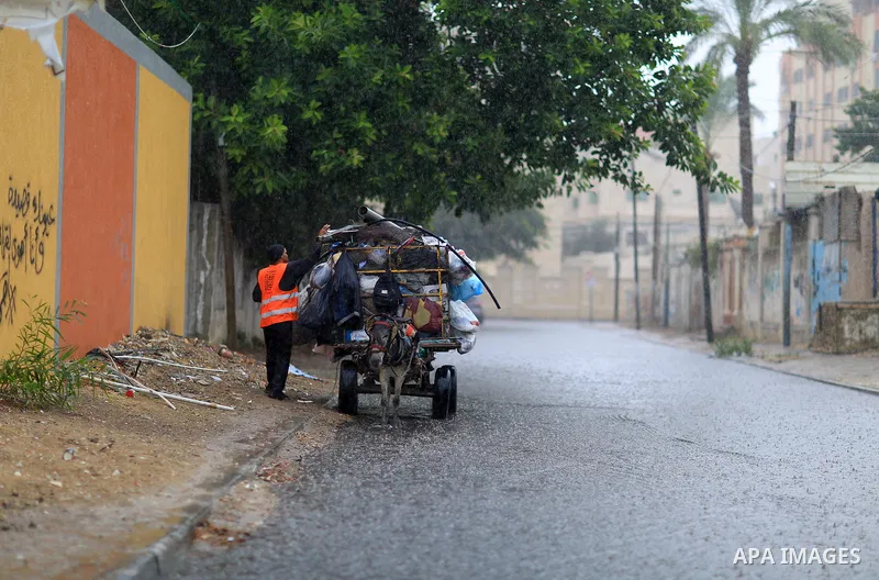 A Palestinian Cleaner works in a street during heavy rains, in Gaza city on October 9, 2017. Photo by Atia Darwish