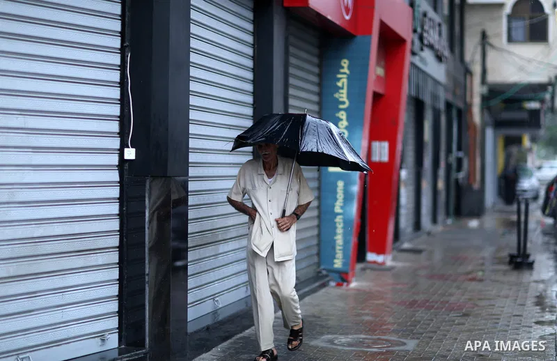 A Palestinian man walks in a street flooded by rain water, in Gaza city on October 9, 2017. Photo by Atia Darwish