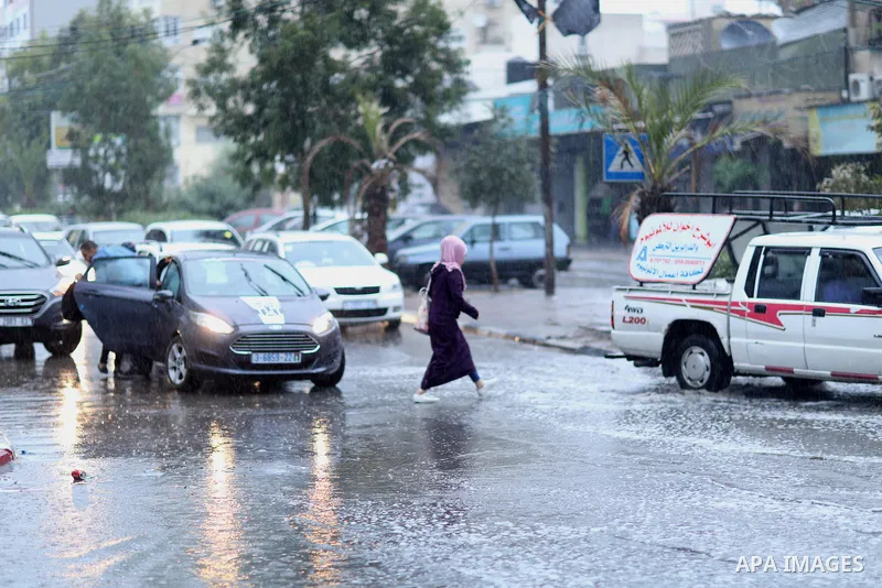 A Palestinian student walks in a street flooded by rain water, in Gaza city on October 9, 2017. Photo by Atia Darwish