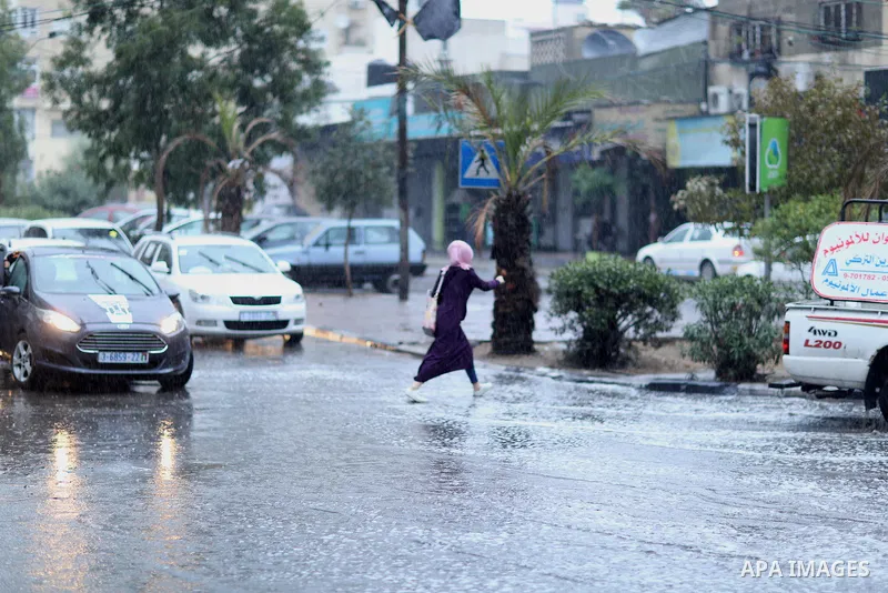A Palestinian student walks in a street flooded by rain water, in Gaza city on October 9, 2017. Photo by Atia Darwish