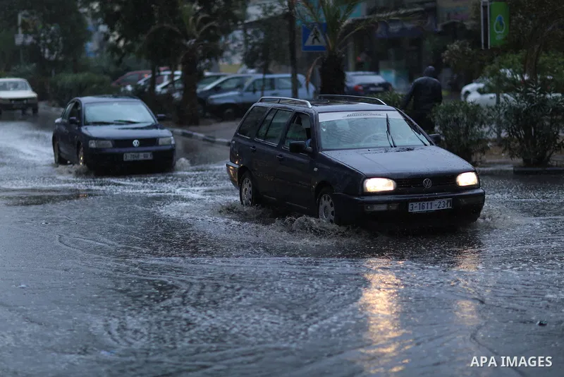 Palestinians walk in a street flooded by rain water, in Gaza city on October 9, 2017. Photo by Atia Darwish