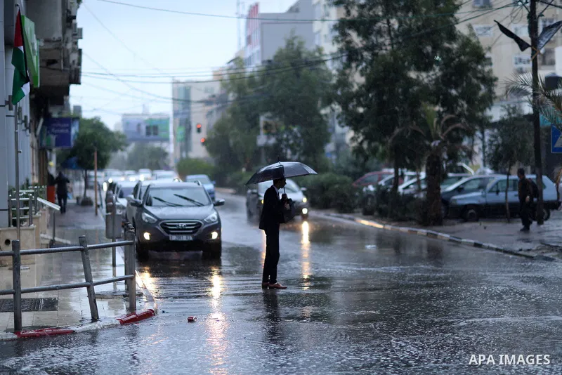 A Palestinian man walks in a street flooded by rain water, in Gaza city on October 9, 2017. Photo by Atia Darwish