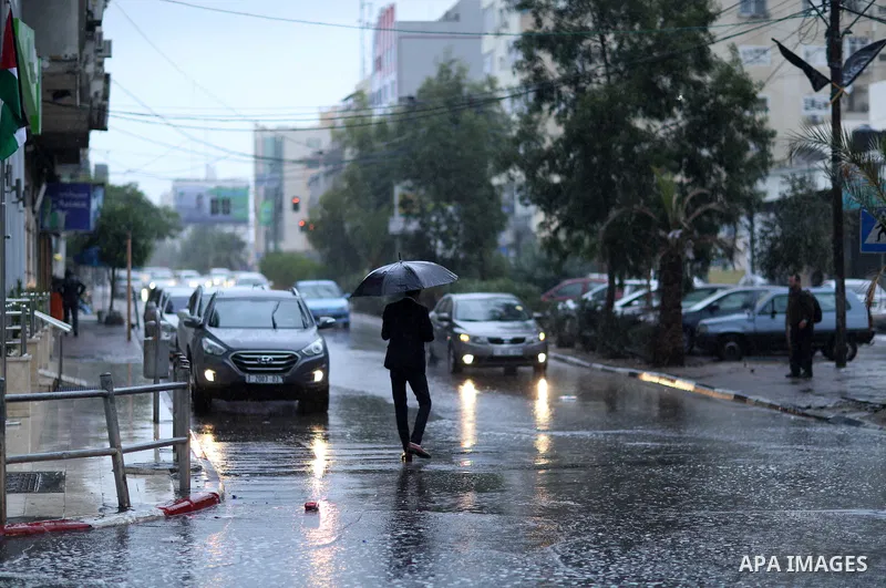 A Palestinian man walks in a street flooded by rain water, in Gaza city on October 9, 2017. Photo by Atia Darwish