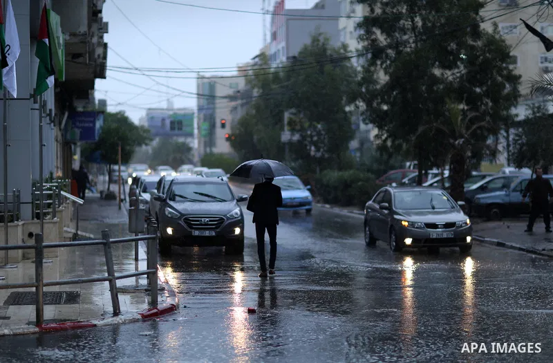 Palestinians walk in a street flooded by rain water, in Gaza city on October 9, 2017. Photo by Atia Darwish