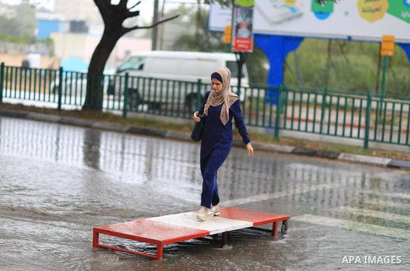 A Palestinian student walks in a street flooded by rain water, in Gaza city on October 9, 2017. Photo by Atia Darwish