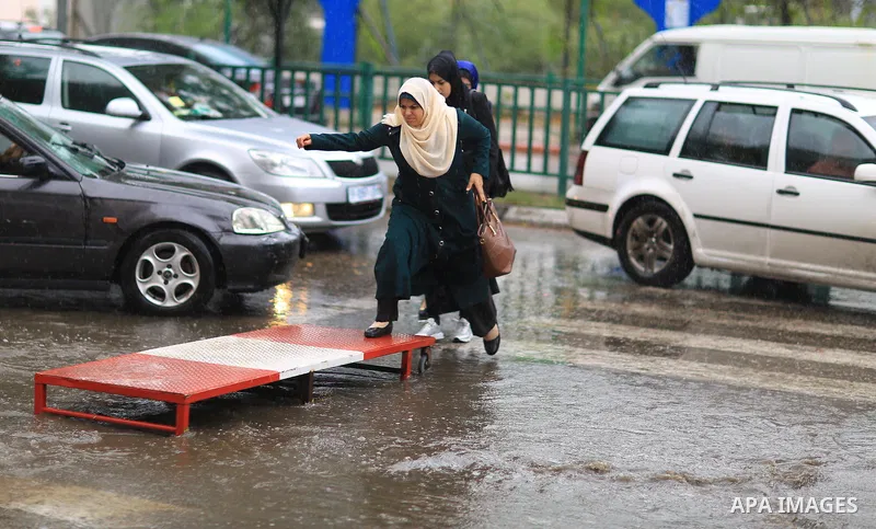 Palestinian students walk in a street flooded by rain water, in Gaza city on October 9, 2017. Photo by Atia Darwish