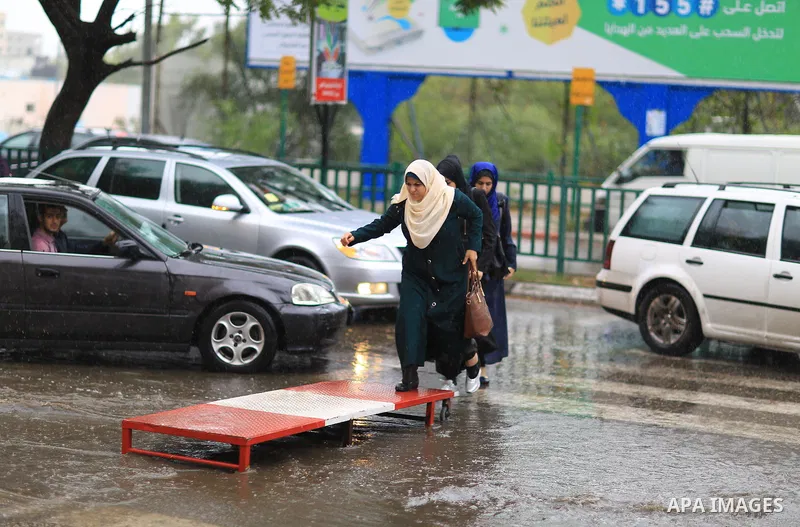 Palestinian students walk in a street flooded by rain water, in Gaza city on October 9, 2017. Photo by Atia Darwish