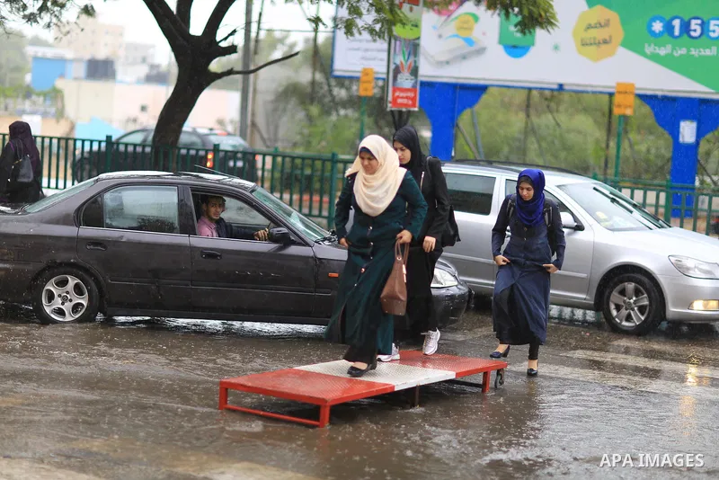Palestinian students walk in a street flooded by rain water, in Gaza city on October 9, 2017. Photo by Atia Darwish
