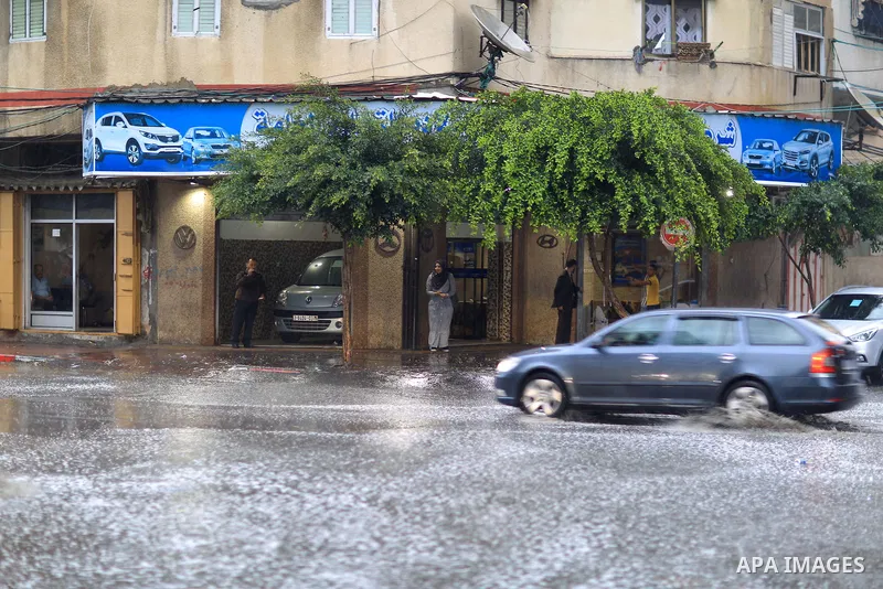 Palestinians walk in a street flooded by rain water, in Gaza city on October 9, 2017. Photo by Atia Darwish