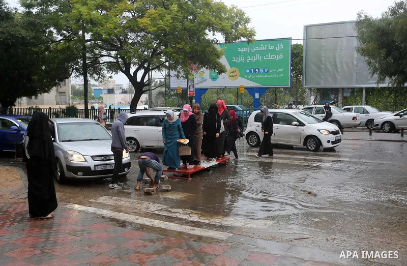 Palestinian students walk in a street flooded by rain water, in Gaza city on October 9, 2017. Photo by Atia Darwish
