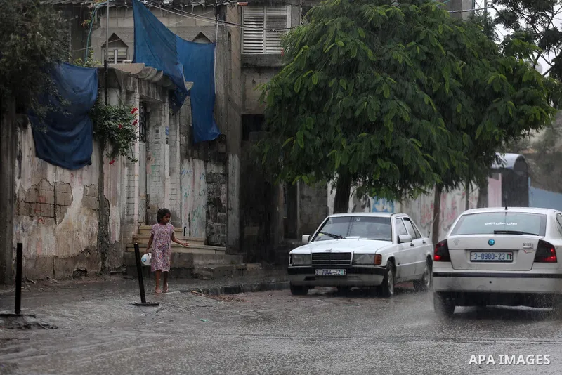A Palestinian girl walks in a street flooded by rain water, in Gaza city on October 9, 2017. Photo by Mohammed Asad