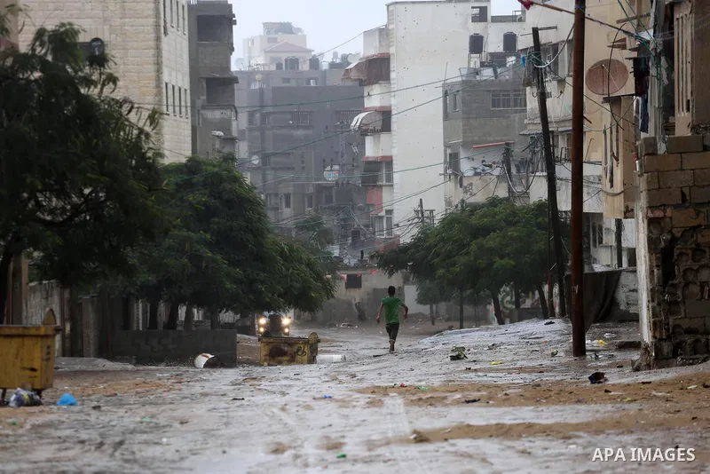 A Palestinian boy walks in a street flooded by rain water, in Gaza city on October 9, 2017. Photo by Mohammed Asad