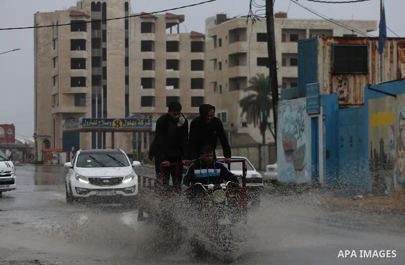 Palestinians walk in a street flooded by rain water, in Gaza city on October 9, 2017. Photo by Mohammed Asad