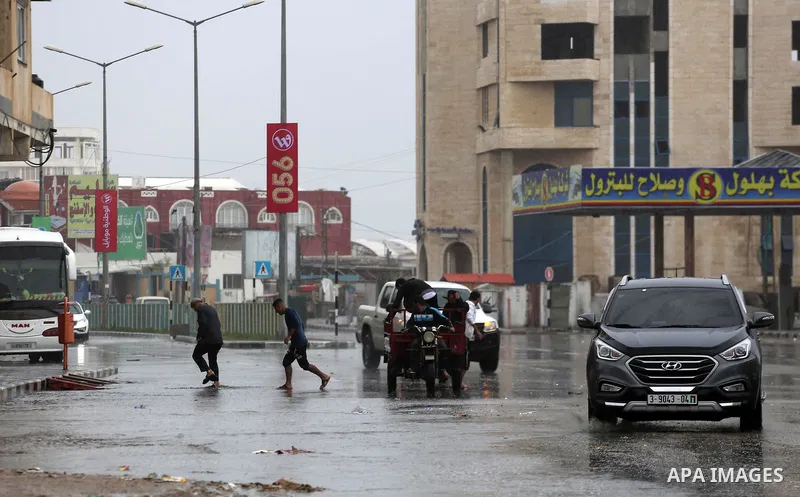 Palestinians walk in a street flooded by rain water, in Gaza city on October 9, 2017. Photo by Mohammed Asad