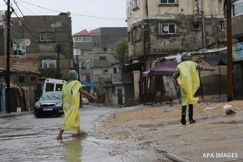Palestinian boys help people during heavy rain, in Gaza city on October 9, 2017. Photo by Mohammed Asad