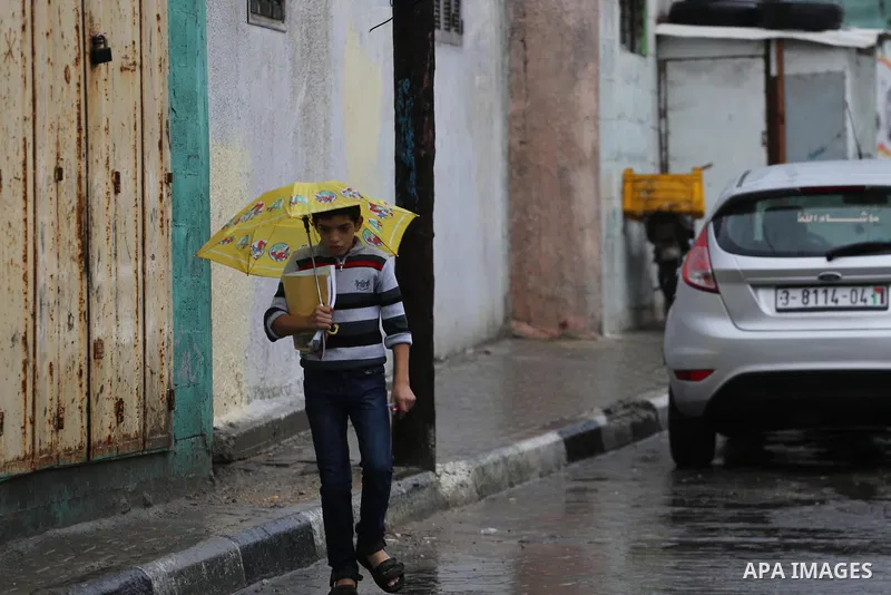 A Palestinian student walks in a street flooded by rain water, in Gaza city on October 9, 2017. Photo by Mohammed Asad