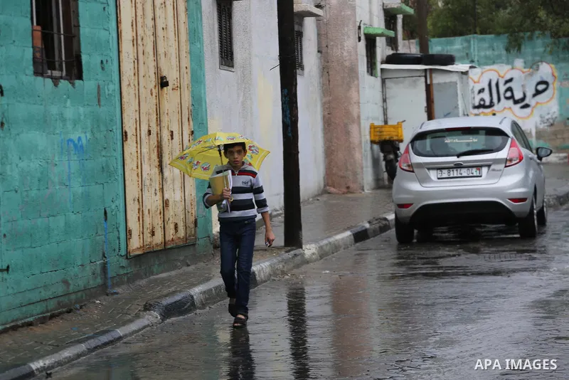 A Palestinian student walks in a street flooded by rain water, in Gaza city on October 9, 2017. Photo by Mohammed Asad