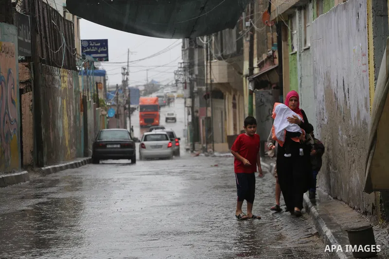 Palestinians walk in a street flooded by rain water, in Gaza city on October 9, 2017. Photo by Mohammed Asad