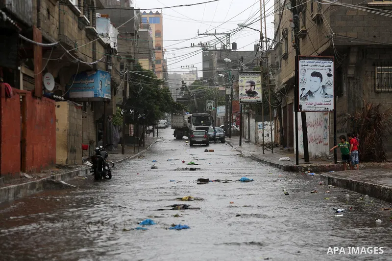 Palestinians walk in a street flooded by rain water, in Gaza city on October 9, 2017. Photo by Mohammed Asad