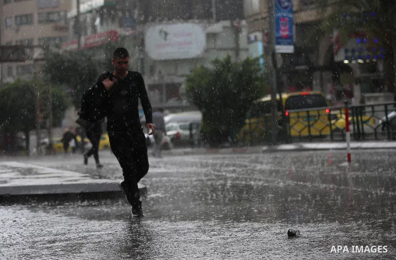 Palestinians walk in a street flooded by rain water, in the West Bank city of Nablus, on October 9, 2017. Photo by Ayman Ameen