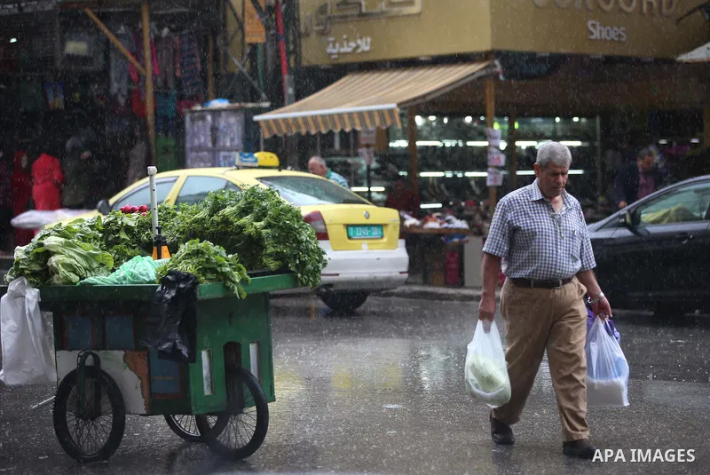 Palestinians walk in a street flooded by rain water, in the West Bank city of Nablus, on October 9, 2017. Photo by Ayman Ameen