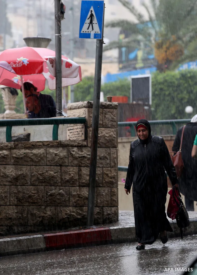 Palestinians walk in a street flooded by rain water, in the West Bank city of Nablus, on October 9, 2017. Photo by Ayman Ameen