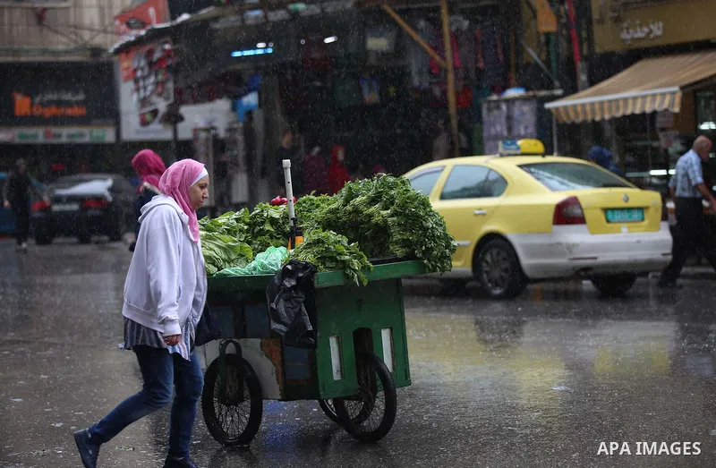 Palestinians walk in a street flooded by rain water, in the West Bank city of Nablus, on October 9, 2017. Photo by Ayman Ameen