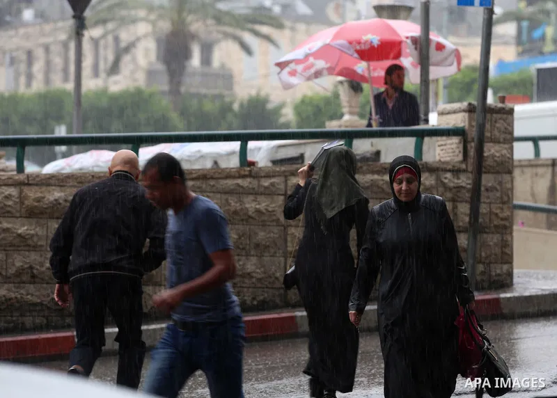 Palestinians walk in a street flooded by rain water, in the West Bank city of Nablus, on October 9, 2017. Photo by Ayman Ameen