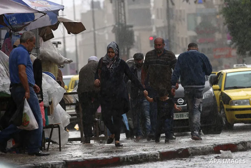 Palestinians walk in a street flooded by rain water, in the West Bank city of Nablus, on October 9, 2017. Photo by Ayman Ameen