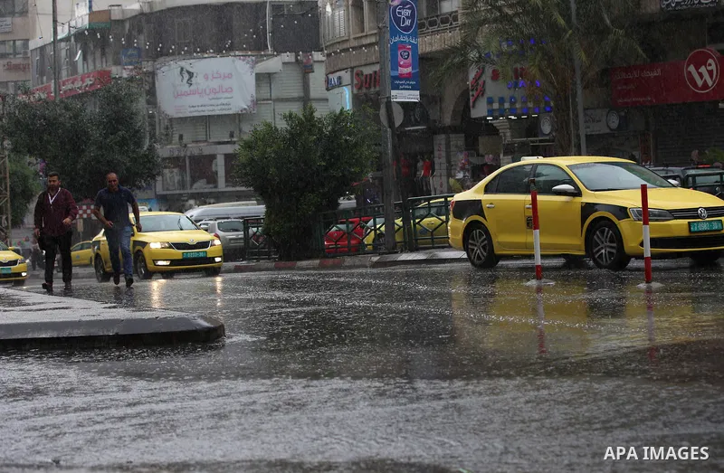 Palestinians walk in a street flooded by rain water, in the West Bank city of Nablus, on October 9, 2017. Photo by Ayman Ameen