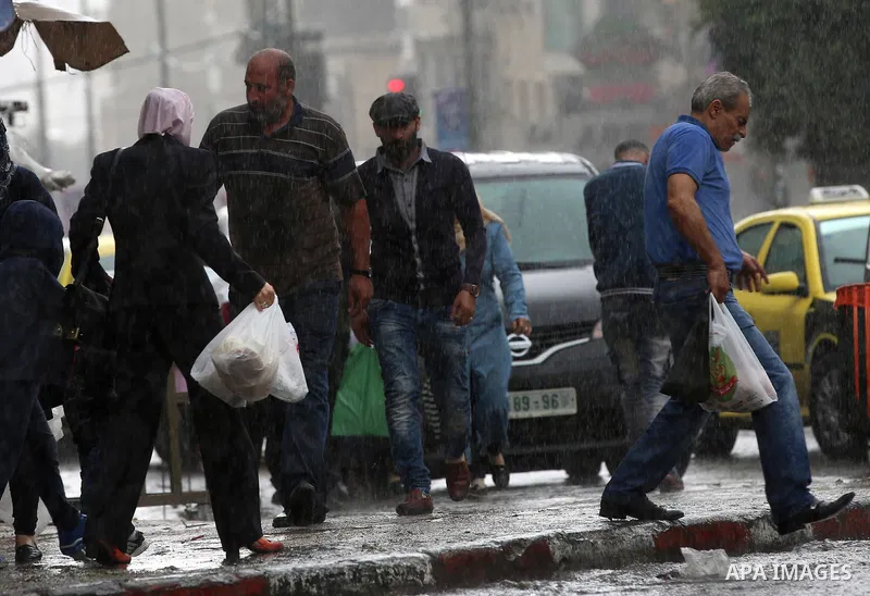 Palestinians walk in a street flooded by rain water, in the West Bank city of Nablus, on October 9, 2017. Photo by Ayman Ameen