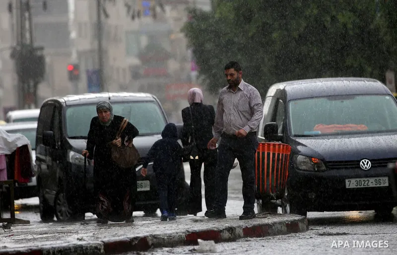 Palestinians walk in a street flooded by rain water, in the West Bank city of Nablus, on October 9, 2017. Photo by Ayman Ameen