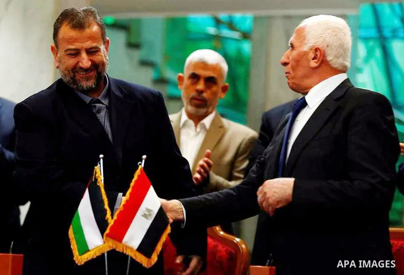 Hamas's new deputy leader Salah al-Aruri (seated L) and Fatah's Azzam al-Ahmad (seated R) sign a reconciliation deal in Cairo on October 12, 2017, as the two rival Palestinian movements ended their decade-long split foll...