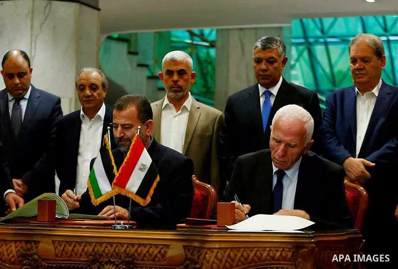 Hamas's new deputy leader Salah al-Aruri (seated L) and Fatah's Azzam al-Ahmad (seated R) sign a reconciliation deal in Cairo on October 12, 2017, as the two rival Palestinian movements ended their decade-long split foll...