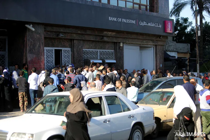 Palestinians of Social Affairs wait in front of Bank of Palestine to withdrew their financial aid in Gaza City on October 29, 2017. Photo by Atia Darwish