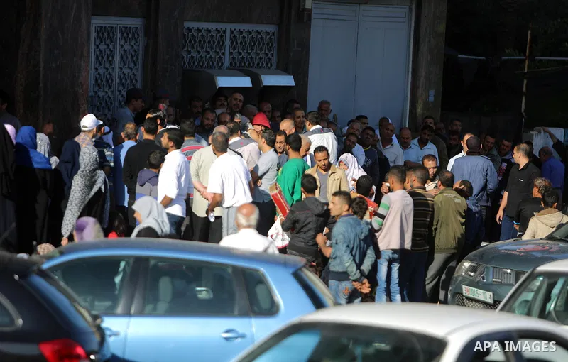 Palestinians of Social Affairs wait in front of Bank of Palestine to withdrew their financial aid in Gaza City on October 29, 2017. Photo by Atia Darwish