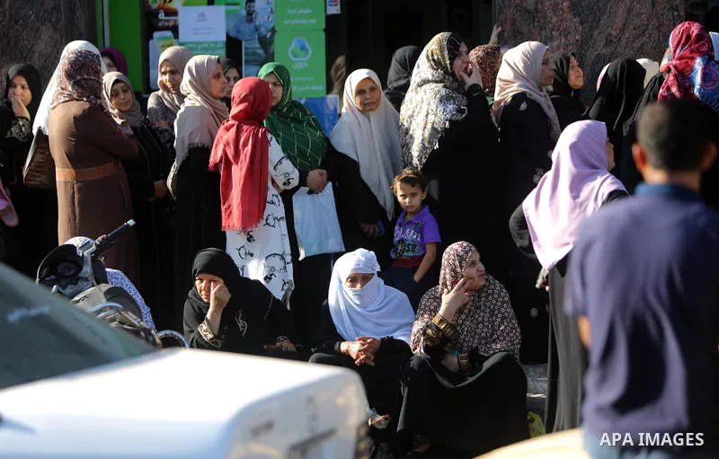 Palestinians of Social Affairs wait in front of Bank of Palestine to withdrew their financial aid in Gaza City on October 29, 2017. Photo by Atia Darwish