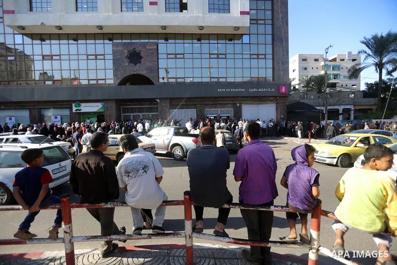 Palestinians of Social Affairs wait in front of Bank of Palestine to withdrew their financial aid in Gaza City on October 29, 2017. Photo by Atia Darwish