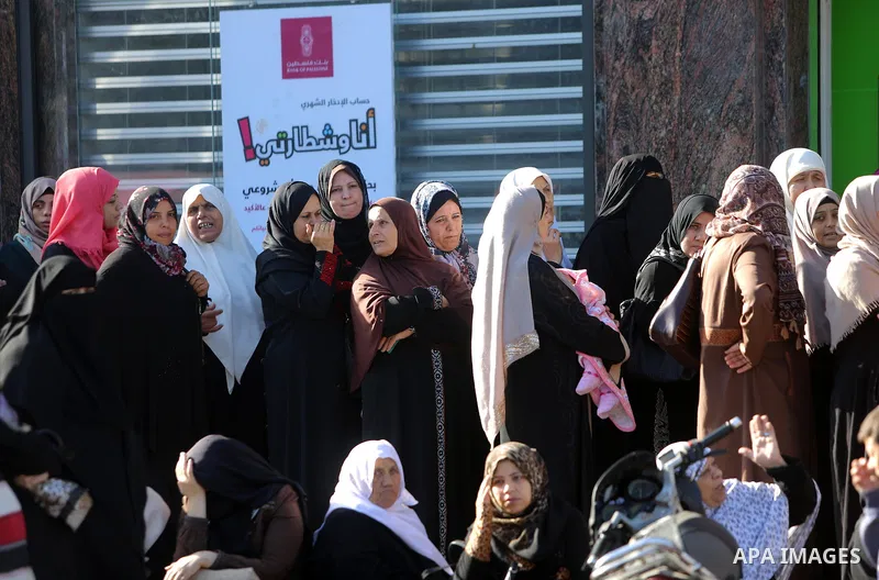 Palestinians of Social Affairs wait in front of Bank of Palestine to withdrew their financial aid in Gaza City on October 29, 2017. Photo by Atia Darwish