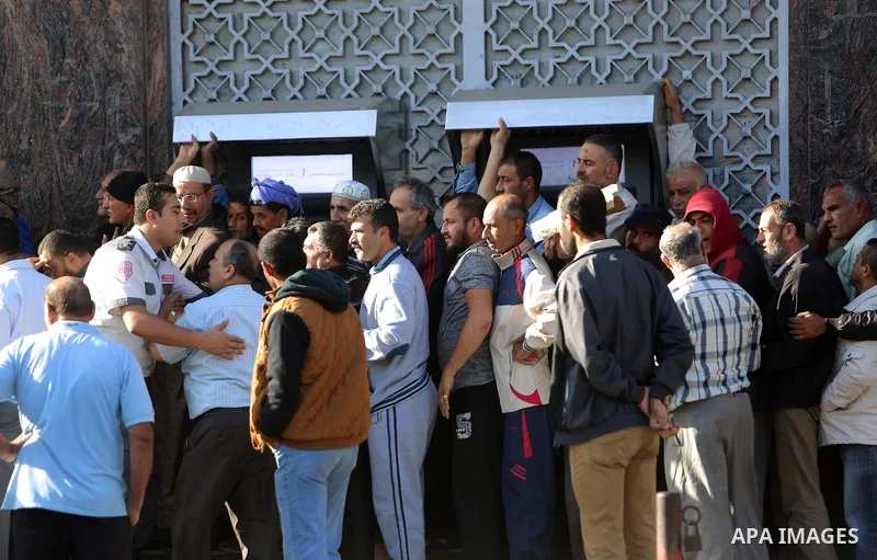 Palestinians of Social Affairs wait in front of Bank of Palestine to withdrew their financial aid in Gaza City on October 29, 2017. Photo by Atia Darwish