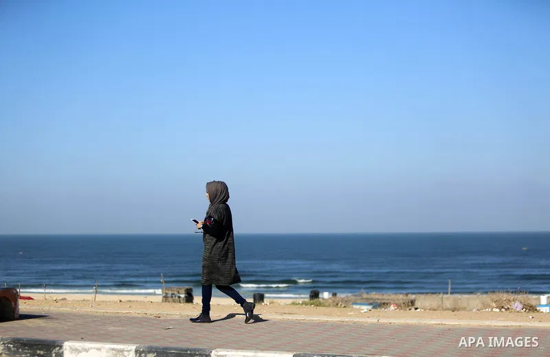 A Palestinian woman walks at the beach of Gaza sea on October 29, 2017. Photo by Atia Darwish