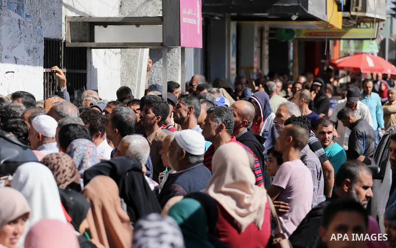 Palestinians of Social Affairs wait in front of Bank of Palestine to withdrew their financial aid in Gaza City on October 29, 2017. Photo by Mohammed Asad