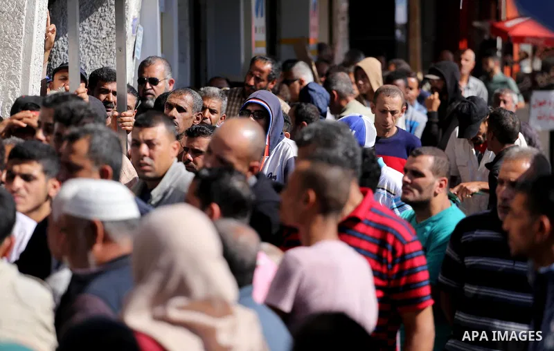 Palestinians of Social Affairs wait in front of Bank of Palestine to withdrew their financial aid in Gaza City on October 29, 2017. Photo by Mohammed Asad