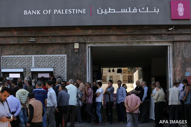 Palestinians of Social Affairs wait in front of Bank of Palestine to withdrew their financial aid in Gaza City on October 29, 2017. Photo by Mohammed Asad