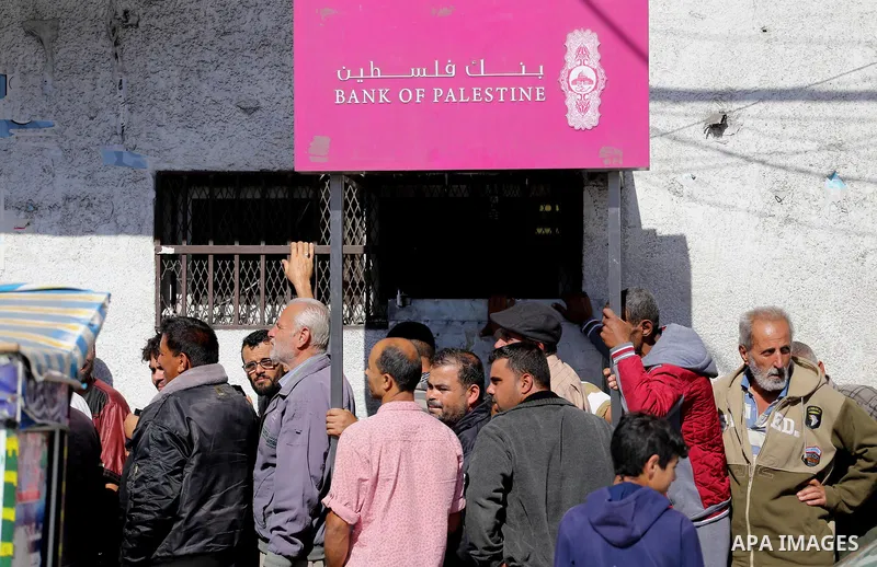 Palestinians of Social Affairs wait in front of Bank of Palestine to withdrew their financial aid in Gaza City on October 29, 2017. Photo by Mohammed Asad