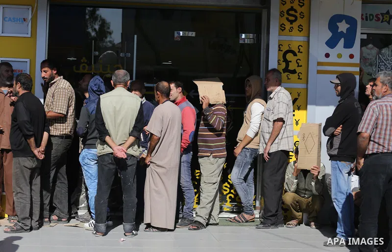 Palestinians of Social Affairs wait in front of Bank of Palestine to withdrew their financial aid in Gaza City on October 29, 2017. Photo by Mohammed Asad