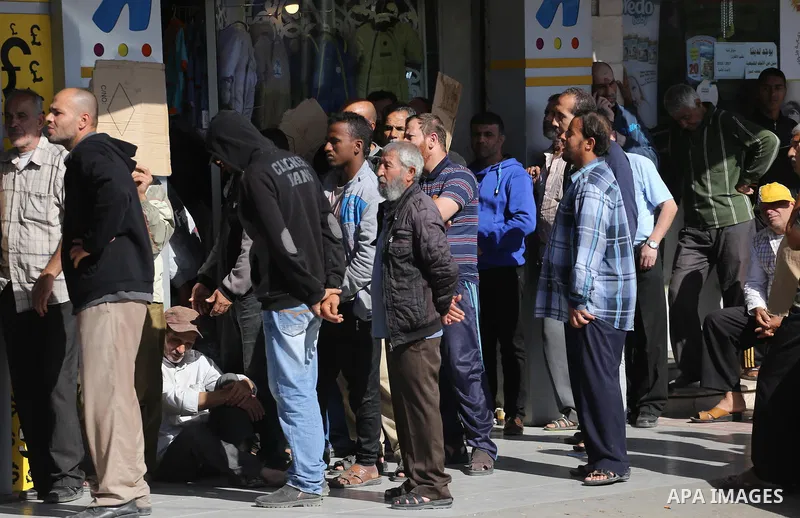 Palestinians of Social Affairs wait in front of Bank of Palestine to withdrew their financial aid in Gaza City on October 29, 2017. Photo by Mohammed Asad