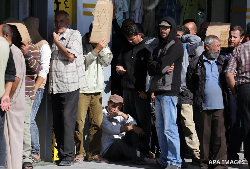 Palestinians of Social Affairs wait in front of Bank of Palestine to withdrew their financial aid in Gaza City on October 29, 2017. Photo by Mohammed Asad