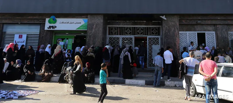 Palestinians of Social Affairs wait in front of Bank of Palestine to withdrew their financial aid in Gaza City on October 29, 2017. Photo by Yasser Qudih