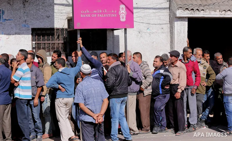 Palestinians of Social Affairs wait in front of Bank of Palestine to withdrew their financial aid in Gaza City on October 29, 2017. Photo by Yasser Qudih